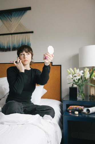 a woman sitting on a bed talking on a cell phone at Redford Hotel in New York