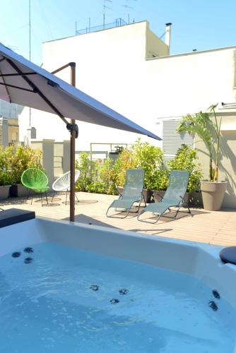 a swimming pool with two chairs and an umbrella at ELLEMENTS - Luxury Rooms in Brindisi