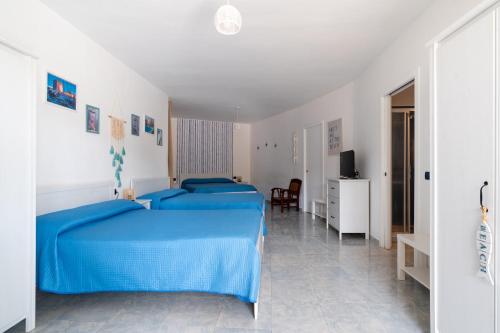 a bedroom with two blue beds and a television at Hotel San Giovanni in Polignano a Mare