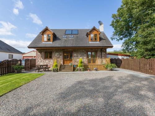a house with a fence and a gravel driveway at Broombank Cottage in Inverness