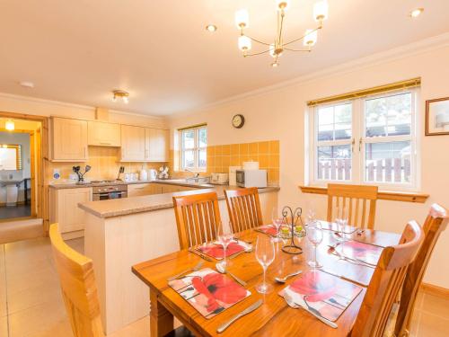 a kitchen and dining room with a wooden table and chairs at Broombank Cottage in Inverness