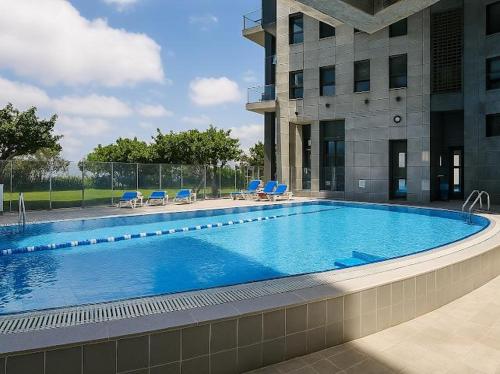 内坦亚Apartment in Netanya的一座带蓝色椅子的大型游泳池和一座建筑