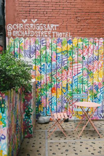 a wall covered in colorful graffiti next to a table at Orchard Street Hotel in New York