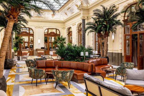 a lobby with a couch and palm trees at NH Collection Prague Carlo IV in Prague