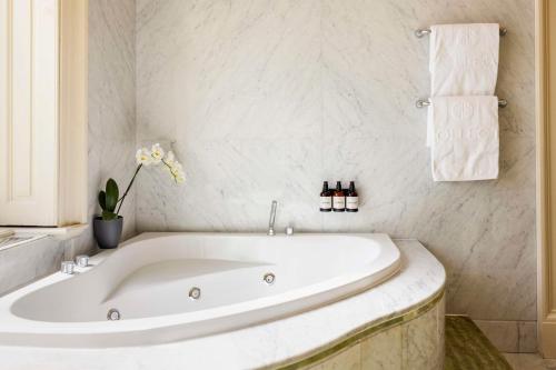 a white bath tub in a bathroom with a window at NH Collection Prague Carlo IV in Prague