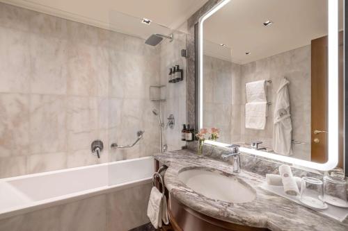a bathroom with a sink and a tub and a mirror at NH Collection Prague Carlo IV in Prague