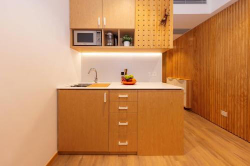 a kitchen with wooden cabinets and a bowl of fruit on the counter at Shama Hub Metro South Hong Kong in Hong Kong