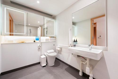 a white bathroom with a sink and a toilet at Shama Hub Metro South Hong Kong in Hong Kong
