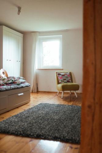 a bedroom with a bed and a chair and a window at Płachty in Liniewo