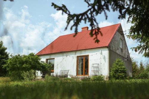 an old white house with a red roof at Płachty in Liniewo