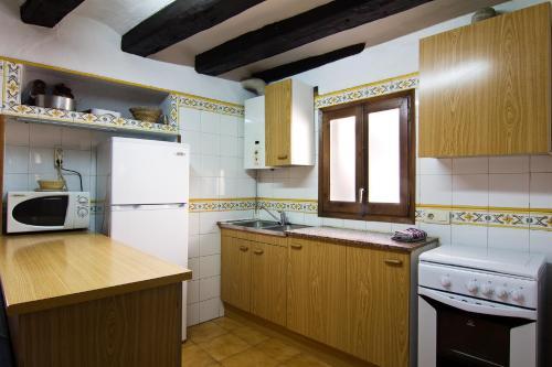 a kitchen with wooden cabinets and a white refrigerator at Casa Rural Baró in Tornafort