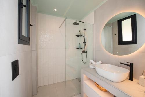 a white bathroom with a sink and a shower at Lefkira Seafront Villa in Évyiros