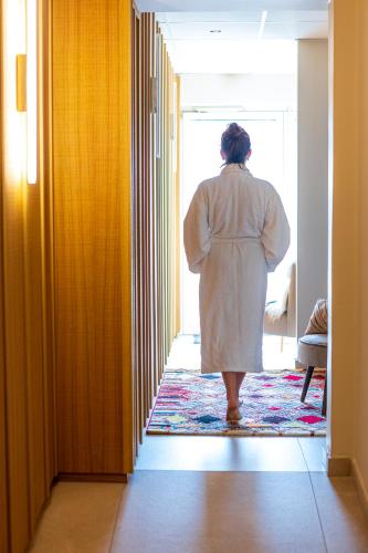 a woman in a white robe looking out of a door at ISKÖ CHALETS-HÖTEL, Col d'Aubisque in Gourette