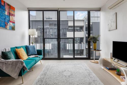 a living room with a blue couch and a large window at Modern Luxury Apartment -Prime South Yarra Location, Melbourne in Melbourne