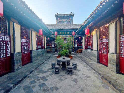 a courtyard of a building with a table and plants at Pingyao Xiangshengyuan Guest House in Pingyao