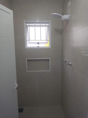 a white bathroom with a window and a shower at Recanto do Sossego in Águas de Lindoia