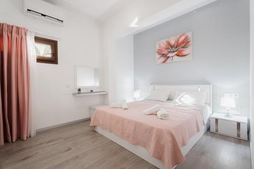 a white bedroom with a bed with a pink blanket at Cozy Guesthouse in Koskinou