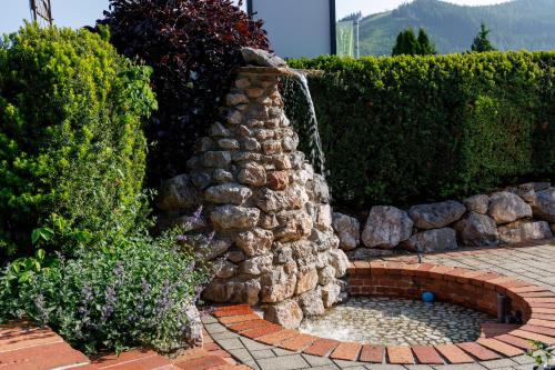 a small fountain in a garden with a stone wall at Aparthotel DAS Hochkönig in Ramsau am Dachstein