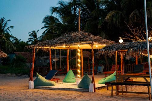 a group of chairs under a straw umbrella on the beach at Mithra Paradise Beach Hotel in Nilaveli