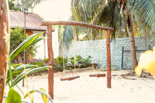 a swing set in the sand in front of a house at Mithra Paradise Beach Hotel in Nilaveli