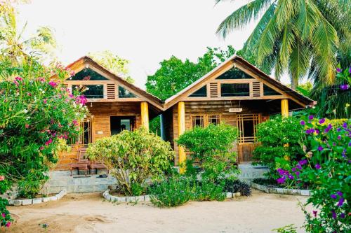 a wooden house with flowers in front of it at Mithra Paradise Beach Hotel in Nilaveli