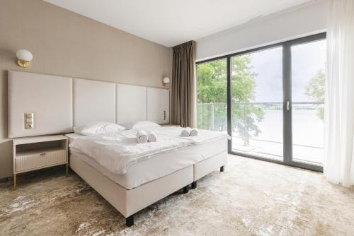 a bedroom with a large bed and a large window at Blue&Green Masurian Hotel in Węgorzewo