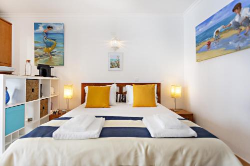 a bedroom with a large bed with yellow and blue pillows at Quinta Velha by MY CHOICE in Cabanas de Tavira