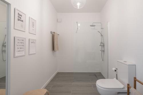 a white bathroom with a toilet and a shower at Barlavento by An Island Apart in Porto Santo