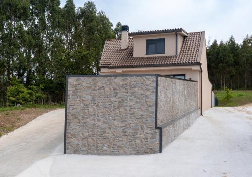 a house with a stone fence in front of a driveway at Casa Muxia in Muxia