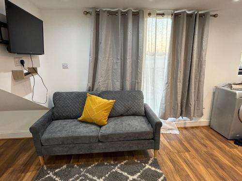 a gray couch with a yellow pillow in a living room at 47a 2bedroom harrow central in Harrow