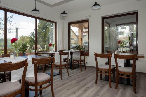 a dining room with tables and chairs and large windows at Penzion u Hanky in Telgárt