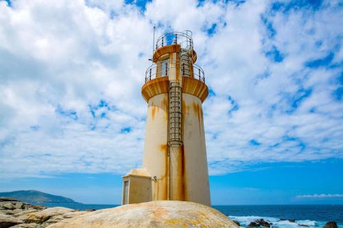 a lighthouse sitting on the rocks near the ocean at Casa Muxia in Muxia