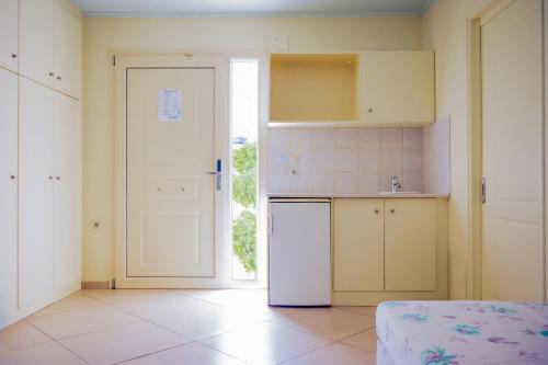a kitchen with a white refrigerator and a door at Princess Hotel in Lassi