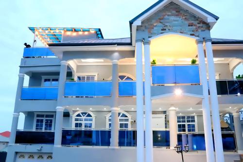 a large white house with blue balconies at Sugarville, Swimming pool with a Rooftop in Accra
