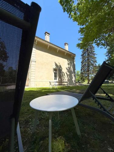 a table and a chair in front of a building at Demeure dans la fôret in Belin-Beliet