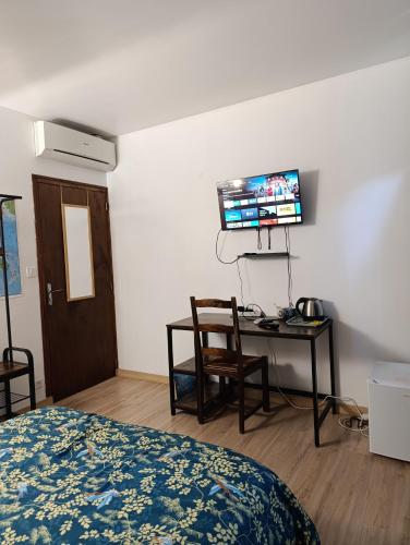 a bedroom with a bed and a desk and a tv at Chez Sam in Villebois
