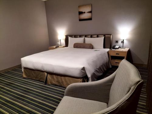 a hotel room with a large bed and a chair at Urban Hotel33 in Kaohsiung