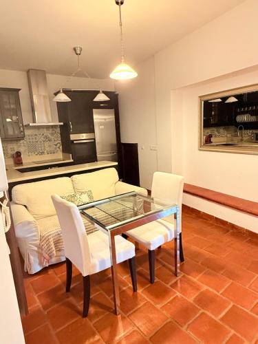 a living room with a glass table and white chairs at Apartamentos Bodeguetas in Constantina