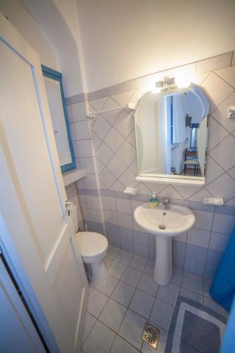 a bathroom with a sink and a toilet and a mirror at Casaprimavera in Katapola