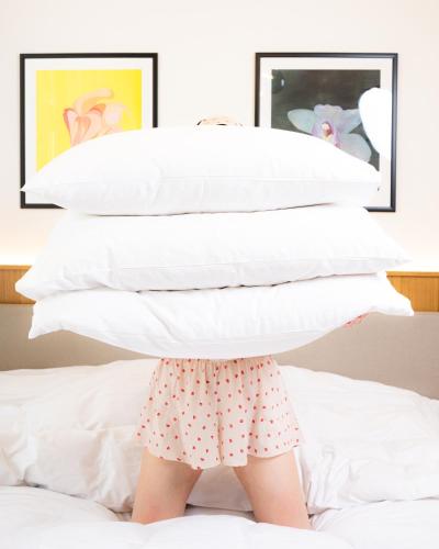a child standing under a pile of pillows on a bed at R16 Residences Prague in Prague
