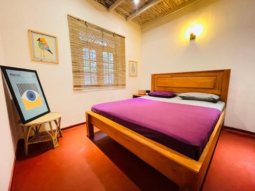 a bedroom with a bed with purple sheets and a painting at Marisol Villa in Unawatuna