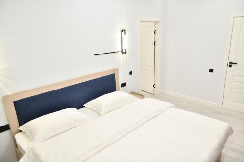 a white bed with a blue headboard in a room at QUT Hotel in Almaty