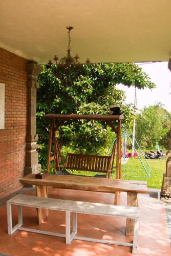 a wooden bench on a porch with a swing at Mesari Cottage Guest House in Buleleng