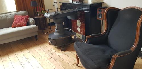 a living room with a stove and a chair and a sink at Sfeervolle vooroorlogse woning nabij centrum in Eindhoven