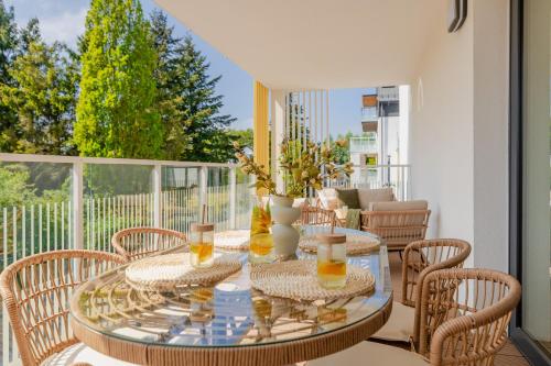 a glass table with chairs on a balcony at POSESJA PLAŻOWA PREMIUM - Apartments & SPA in Grzybowo