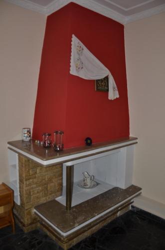 a room with a fireplace with a red wall at Pension Vergina in Vergina