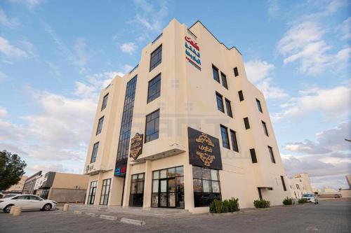 a tall white building with a sign on it at لميك للشقق المخدومة in Al Bukayriyah