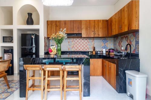 a kitchen with a black counter and wooden cabinets at Villa Amaia Canggu in Kerobokan