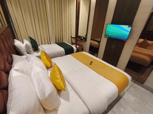 two beds in a hotel room with a flat screen tv at Hotel Ocean Residency Thane West in Thane