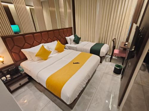 a hotel room with two beds with yellow and white pillows at Hotel Ocean Residency Thane West in Thane